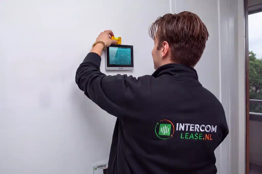 Monteur van Intercom-Lease hangt een witte 7-inch Akuvox-binnenmonitor op (impressie)
